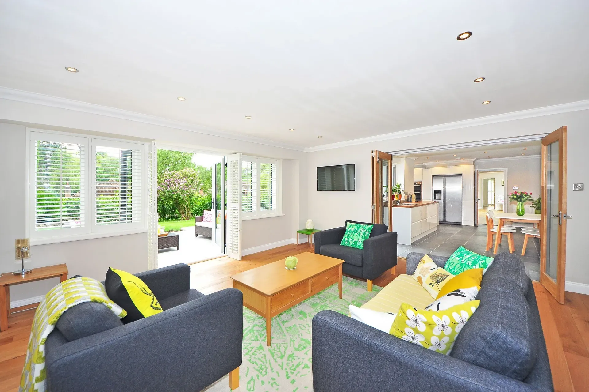 A bright open-plan living room with folding doors onto a garden, looking through to the kitchen
